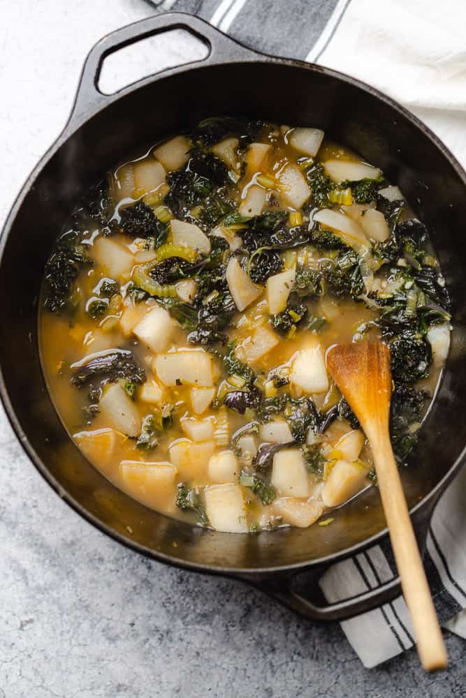 cooked kale and turnips in broth in a cast iron dutch oven