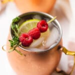 pretty sugar free raspberry moscow mule in a copper mug with fresh lime raspberries and thyme