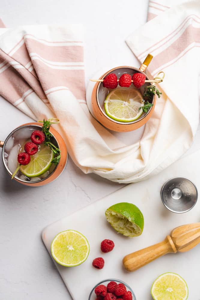 overhead view of two moscow mule mugs with raspberry and lime 