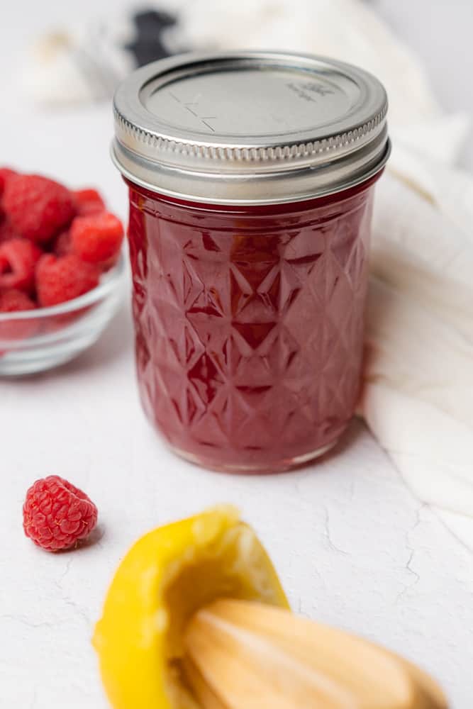small mason jar of sugar free raspberry simple syrup with lemon and fresh raspberries 