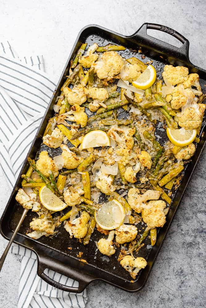 delicious cast iron baking sheet with roasted cauliflower and asparagus with lemon and parmesan cheese