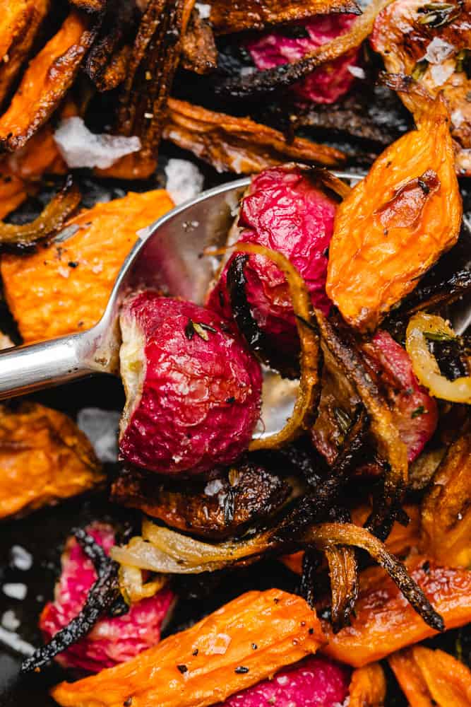 closeup shot of roasted radishes and carrots with a spoon