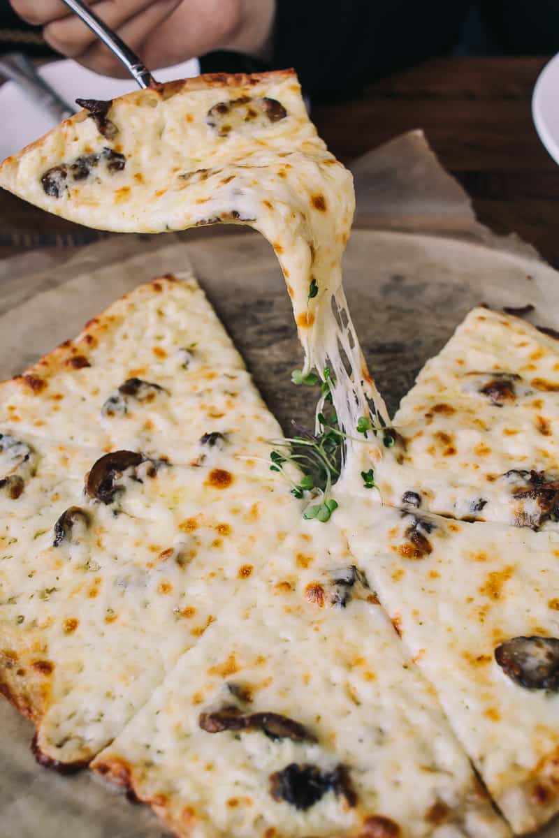 cheese pizza with a slice being pulled out with mushrooms