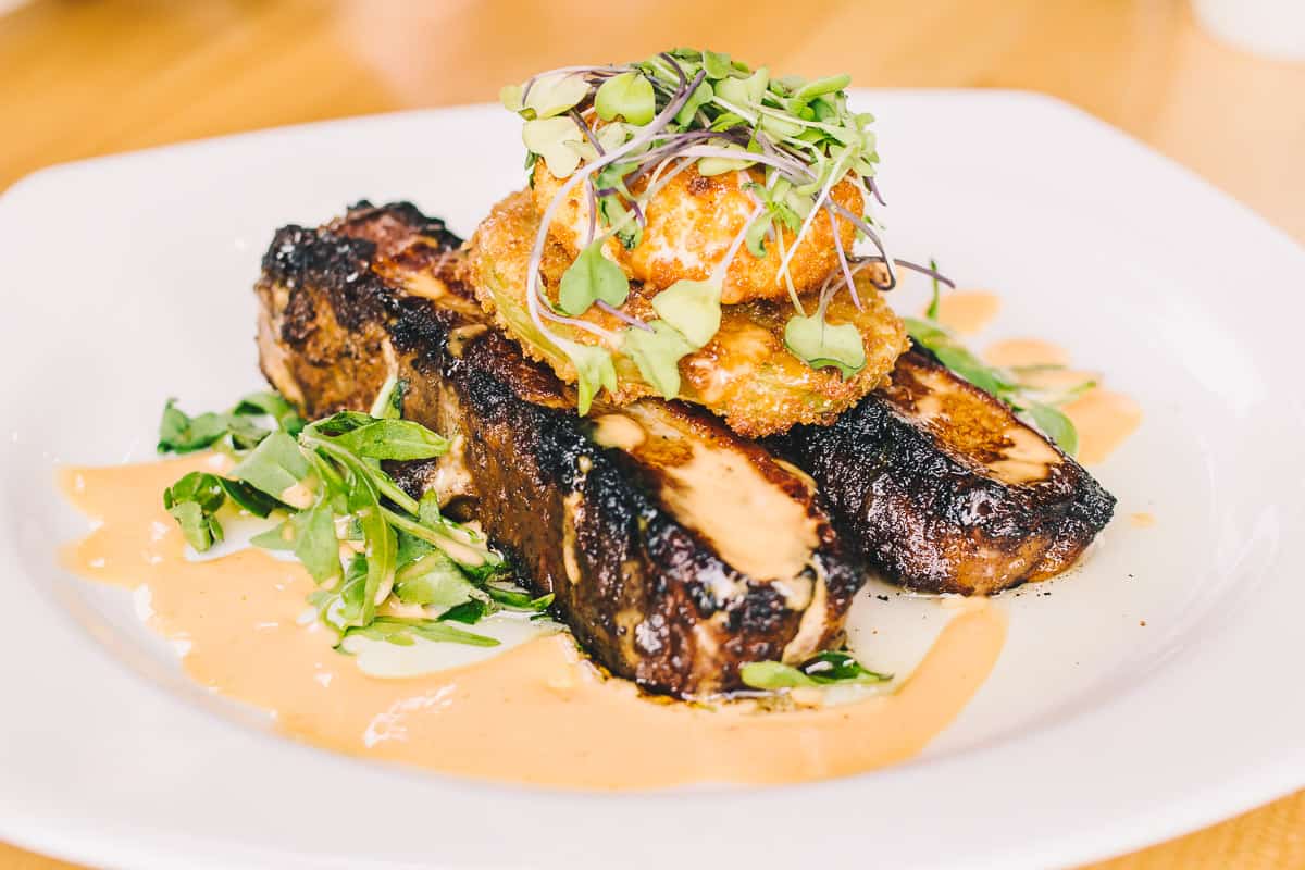 pork belly topped with fried green onions and microgreens and spicy aioli