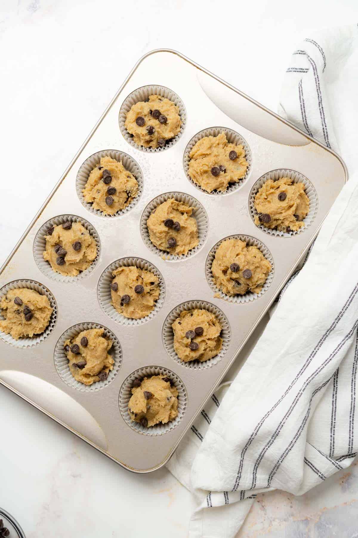 raw banana muffin batter in a muffin tin topped with chocolate chips 