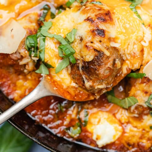 flat lay of cast iron meatballs baked with cheese and basil