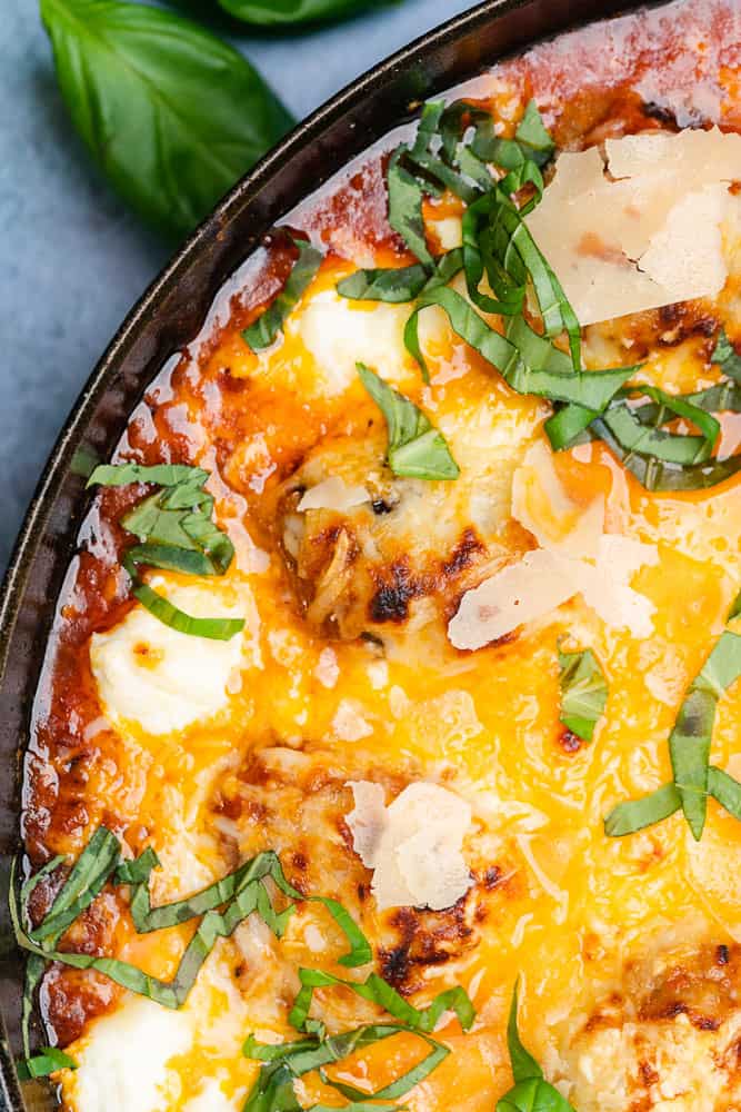 cheesy baked cast iron meatballs in a skillet with basil