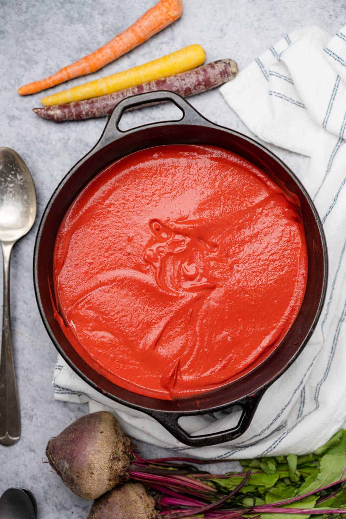 smooth and creamy bright red beet soup with carrots in a cast iron dutch oven