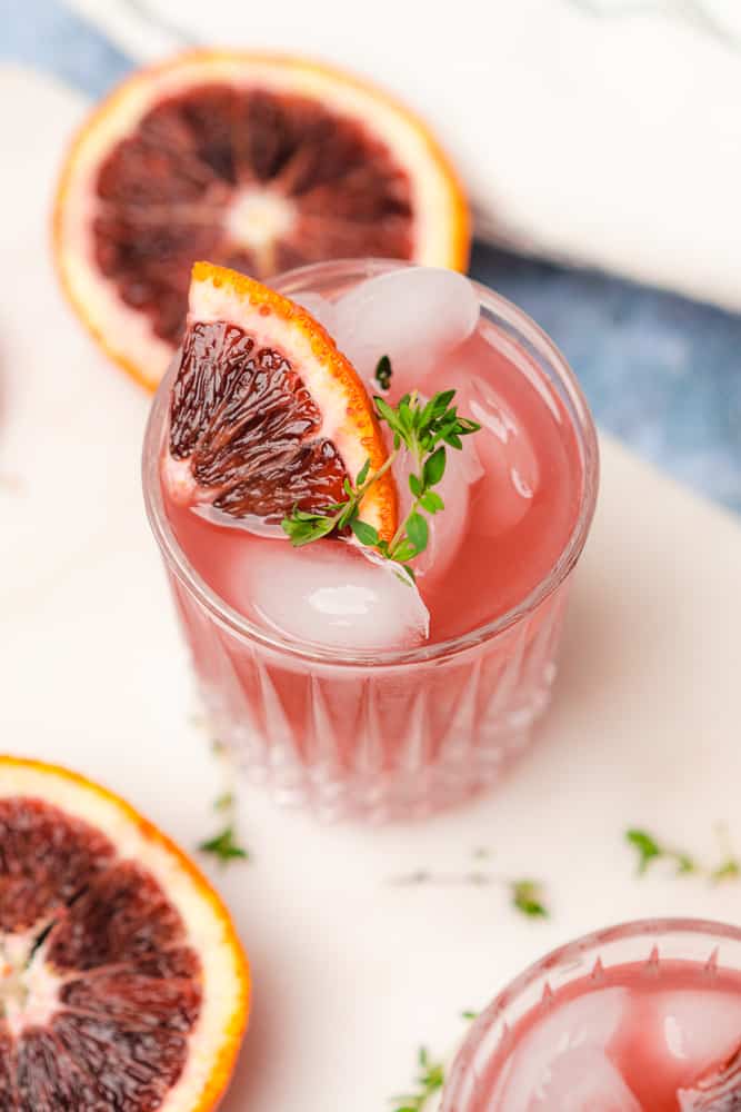 45 degree shot of a blood orange gin cocktail with blood orange and fresh thyme