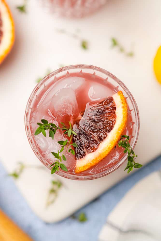 flat lay of blood orange gin cocktail with blood orange slices and fresh thyme