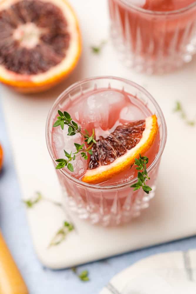45 degree shot of blood orange cocktail with fresh thyme