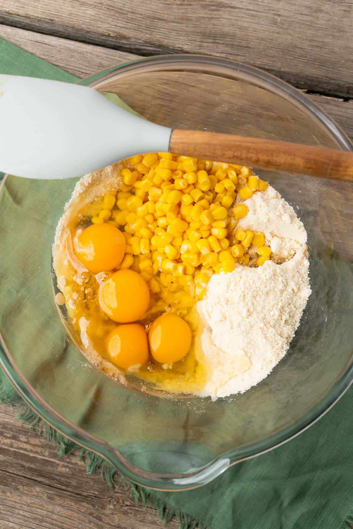 keto cornbread ingredients with whole kernel corn and 4 whole eggs in a glass bowl