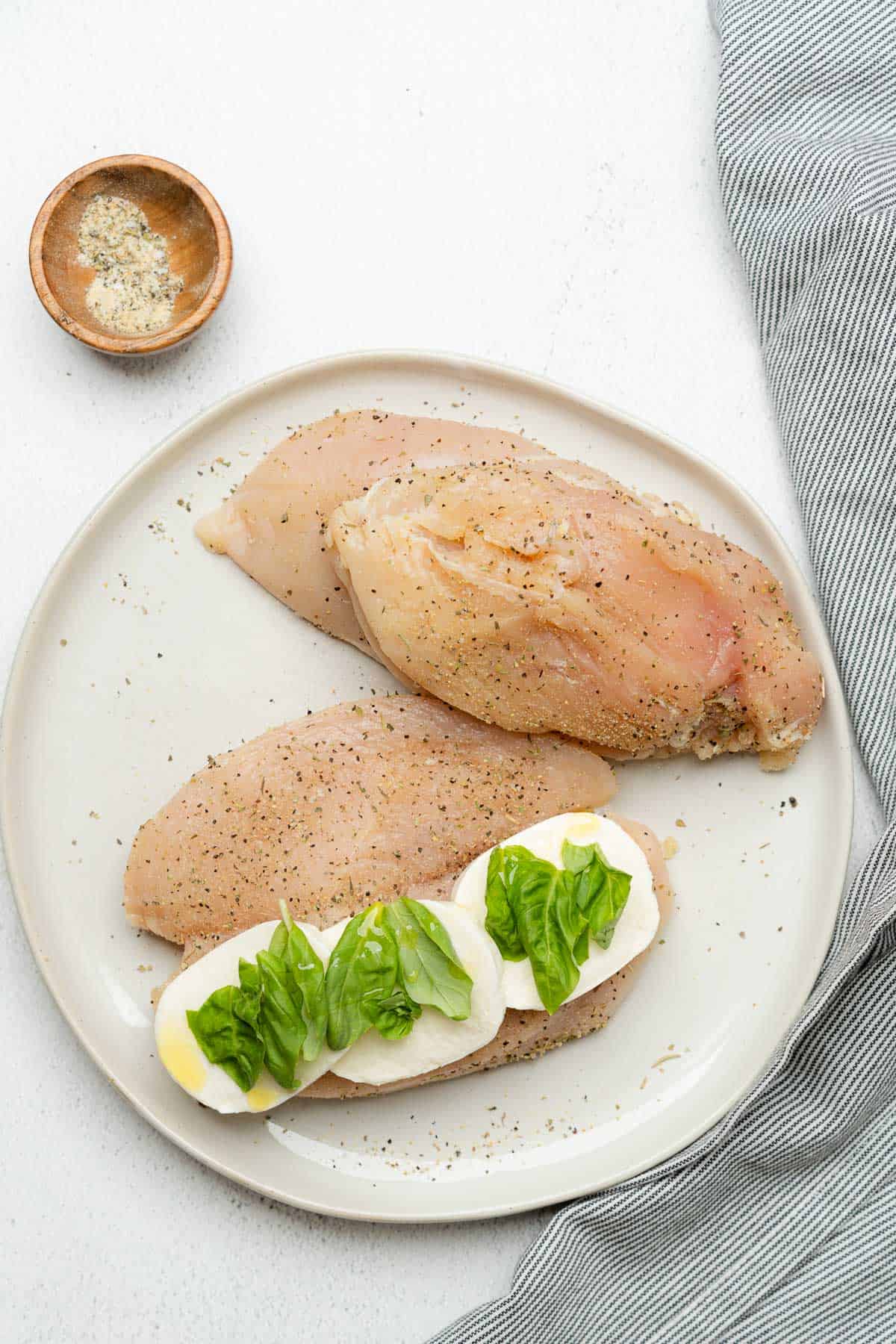 raw chicken breasts being stuffed with fresh basil and mozzarella
