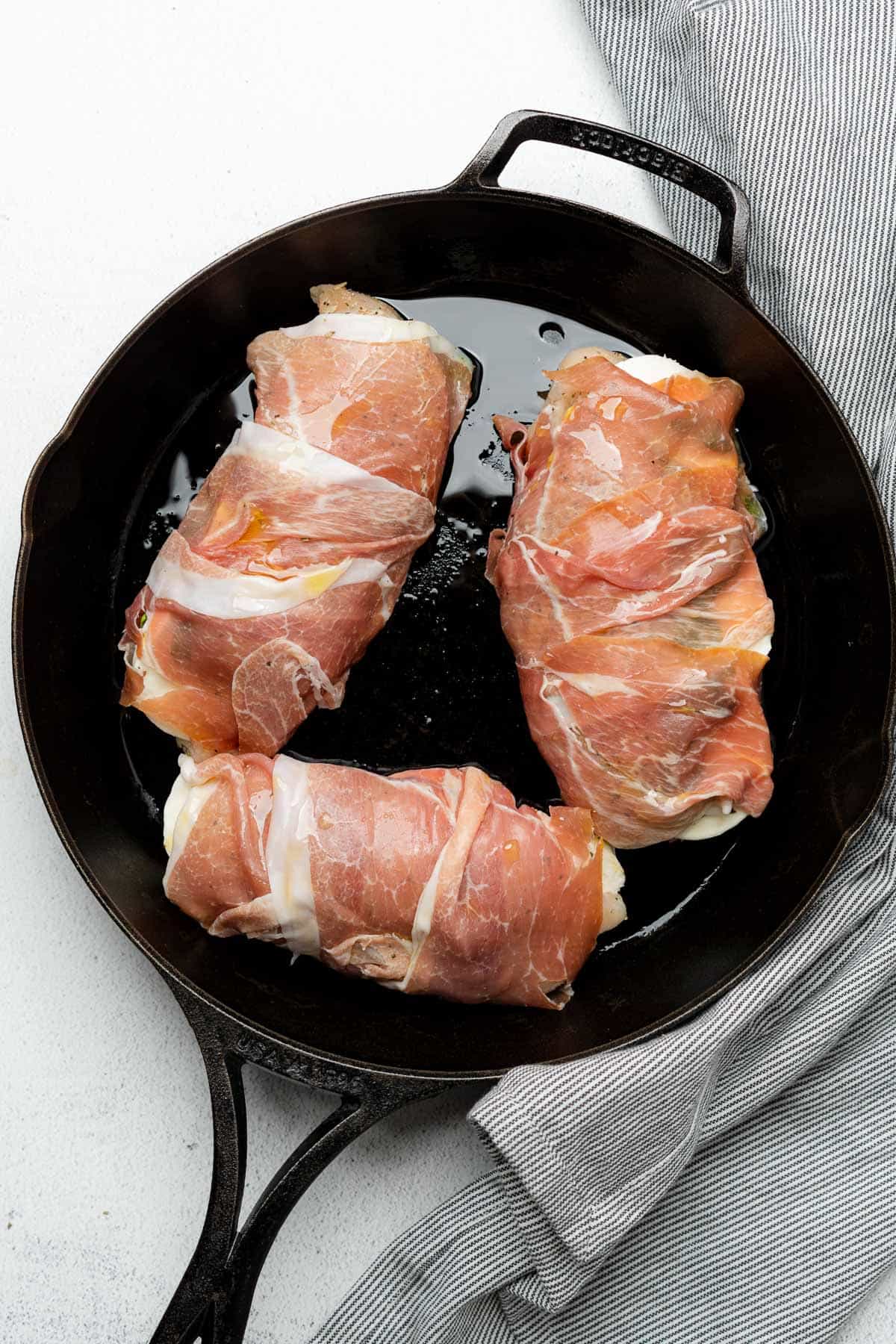 wrapped chicken with toothpicks in a greased cast iron skillet 
