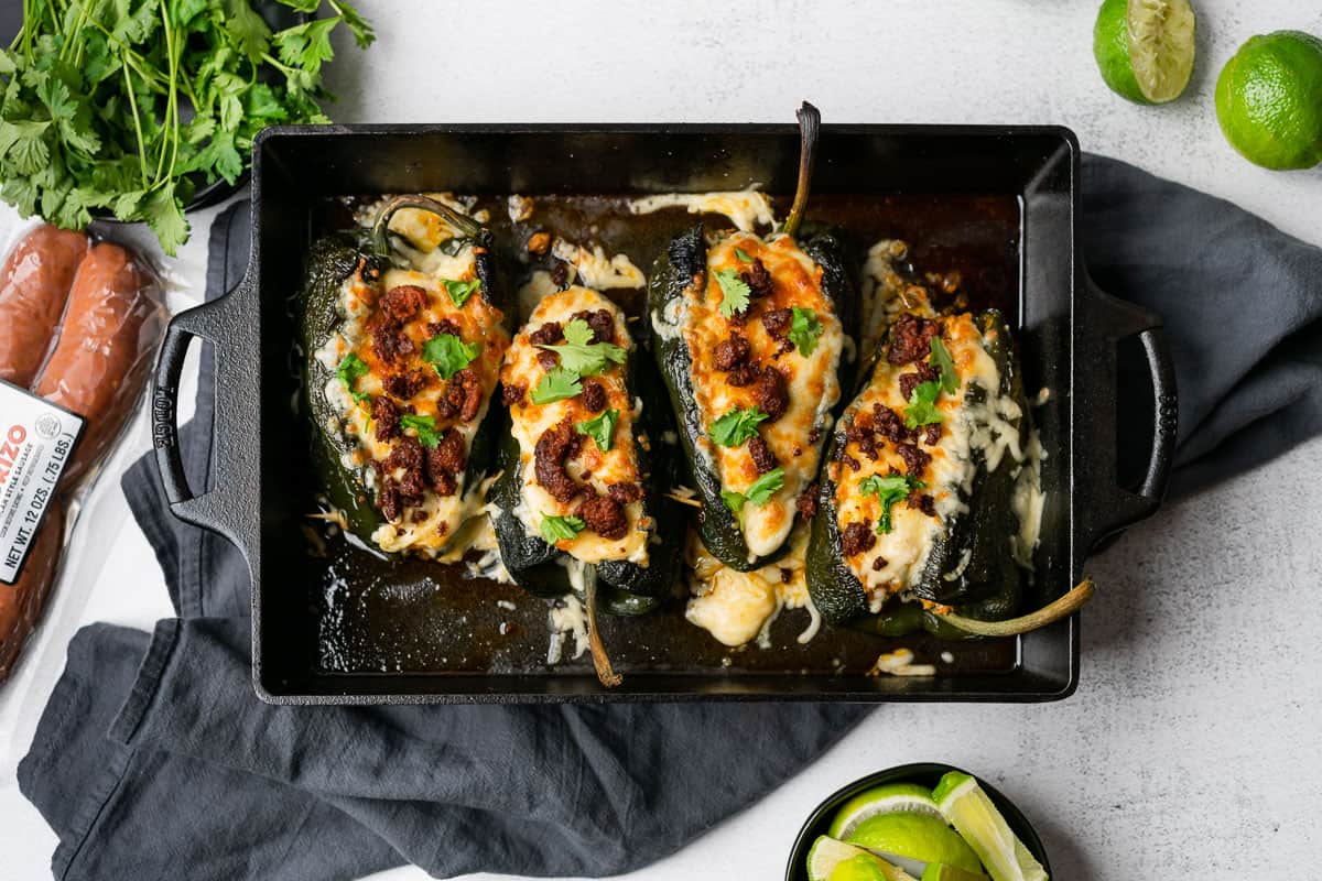 chorizo stuffed poblano peppers with limes and cilantro in a cast iron casserole dish
