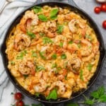 pan of creamy mozzarella shrimp pasta with basil and tomatoes in a cast iron skillet