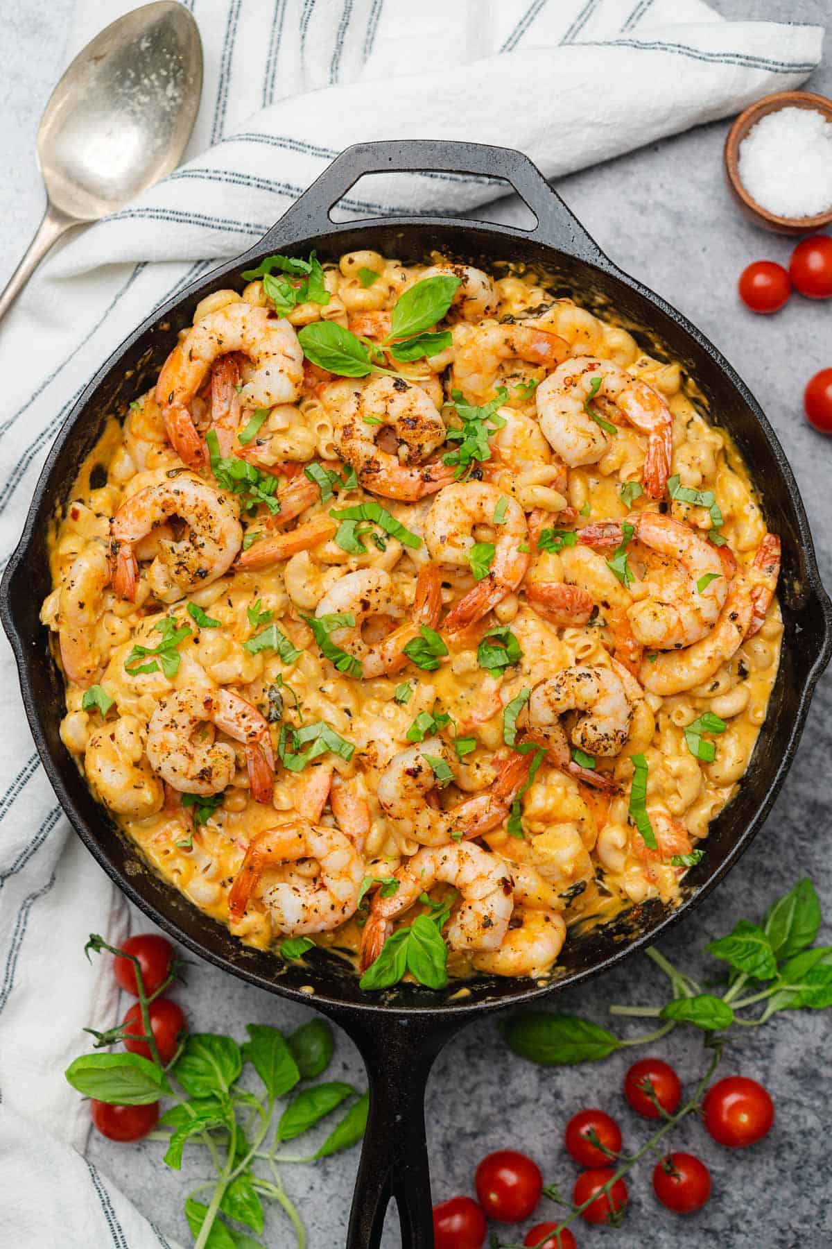 pan of creamy mozzarella shrimp pasta with basil and tomatoes in a cast iron skillet