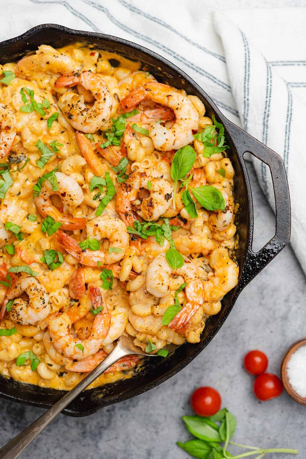 creamy mozzarella shrimp pasta with fresh basil in a cast iron skillet with tomatoes