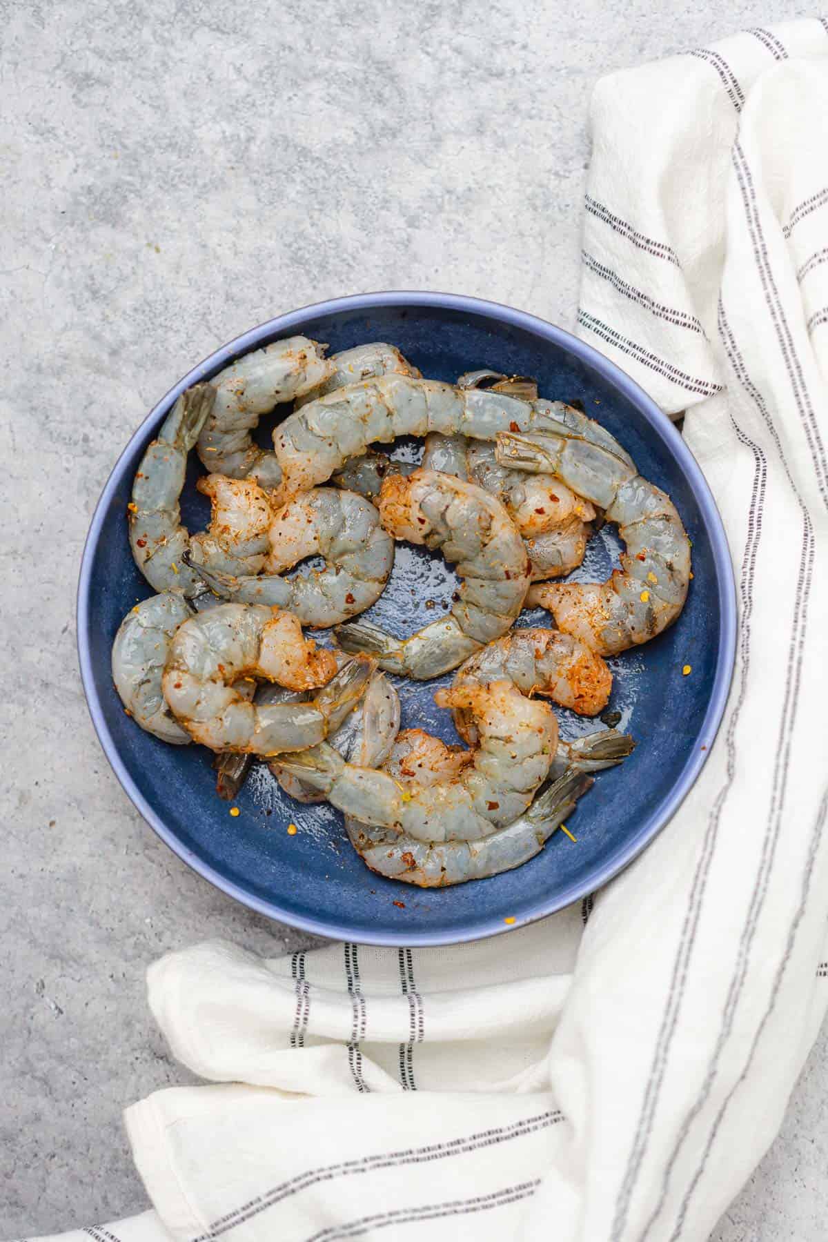 raw shrimp in a bowl with seasonings 