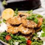 eggplant milanese on a white plate with arugula salad
