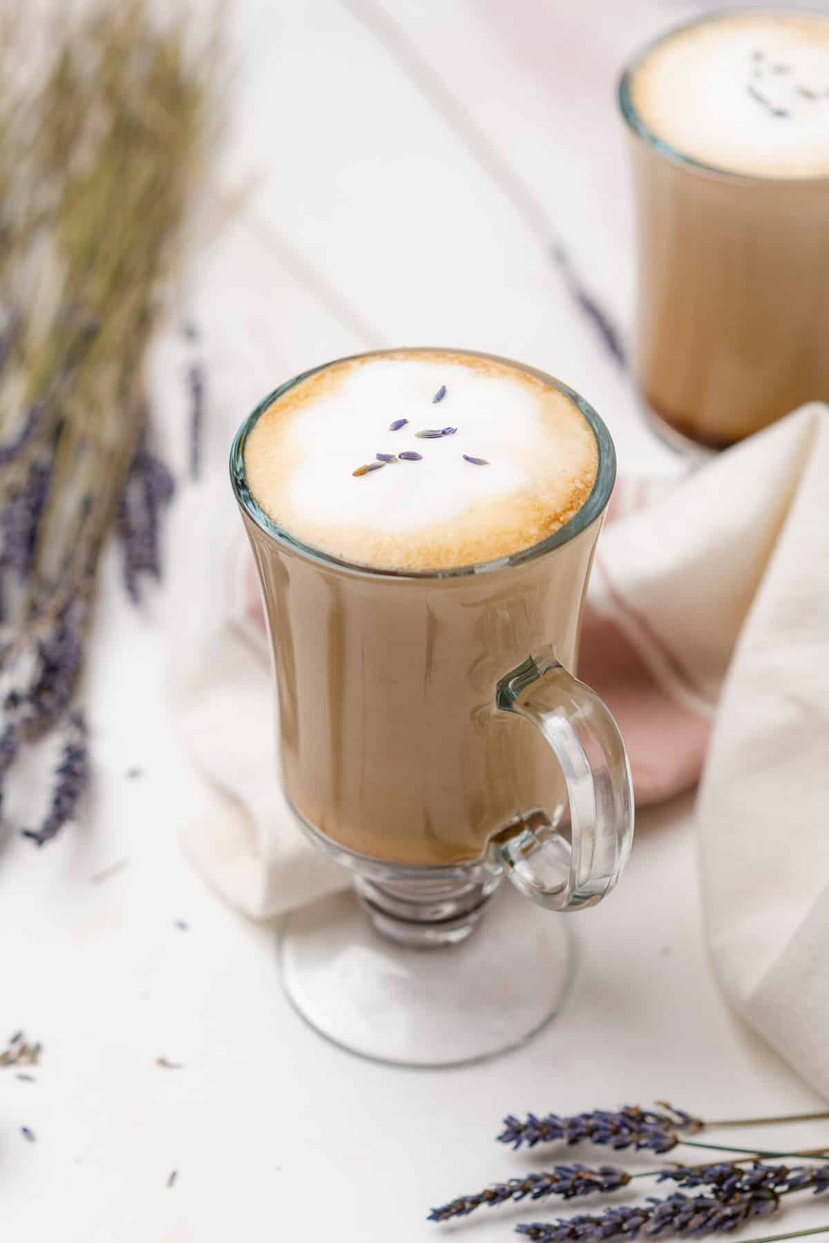 irish coffee mug with a lavender latte in it surrounded by lavender buds