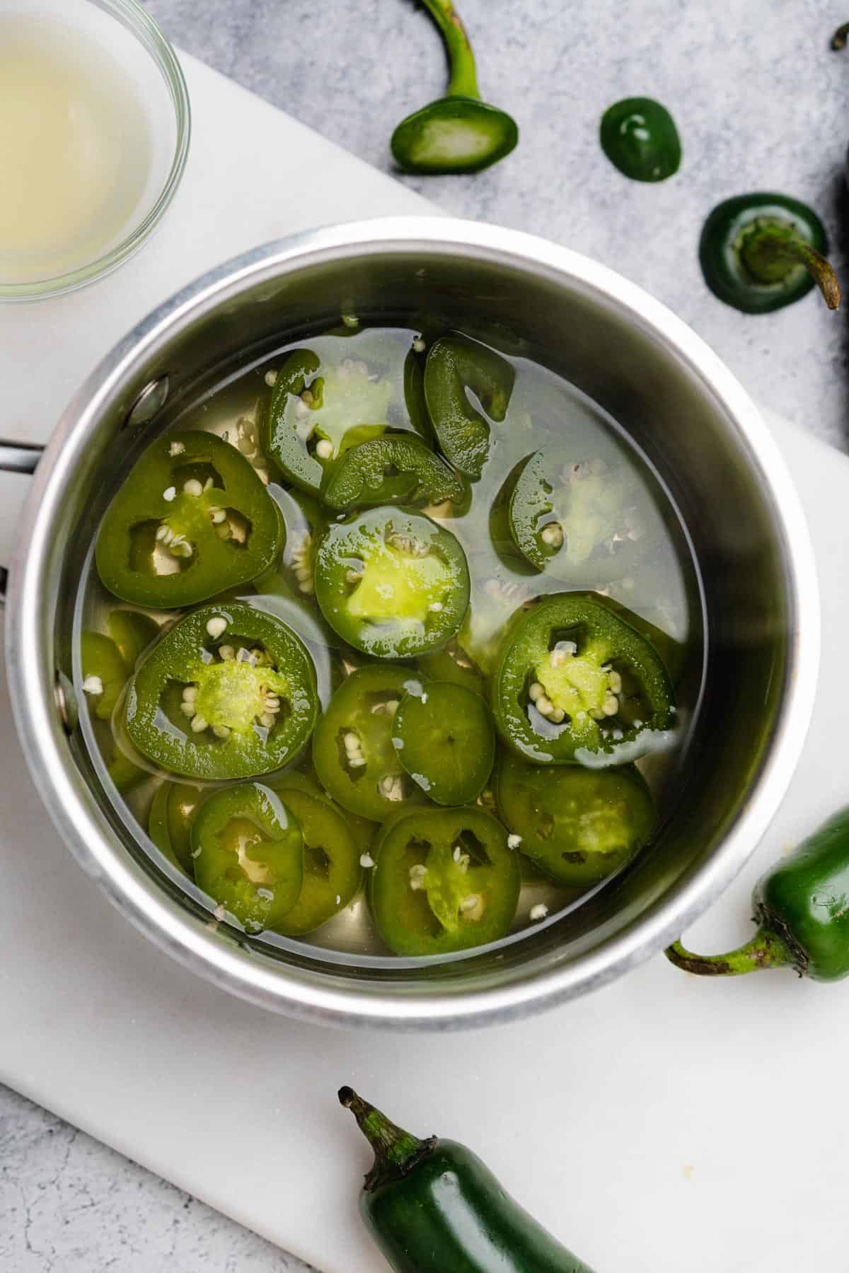 cooked jalapenos in water in a sauce pan