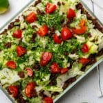 keto 7 layer dip with chorizo with lettuce cilantro and tomatoes in glass casserole dish