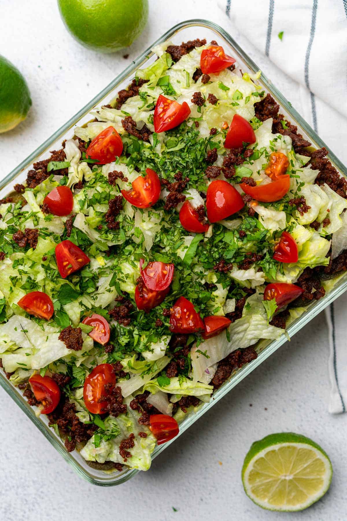 keto 7 layer dip with chorizo with lettuce cilantro and tomatoes in glass casserole dish