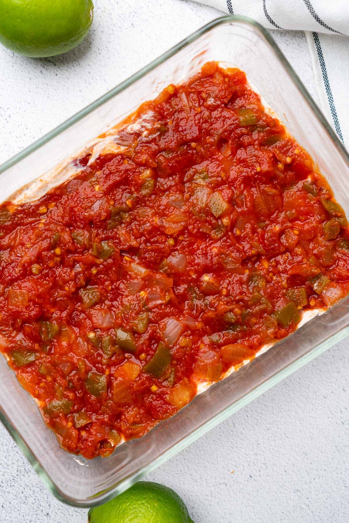 chunky salsa layered on top of seasoned sour cream in a glass casserole dish