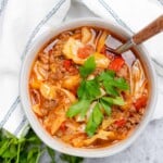 bowl of keto cabbage roll soup in a grey bowl with a white and blue striped napkin with parsley