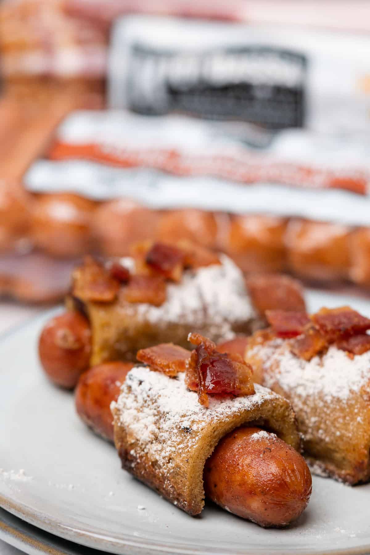 keto french toast pigs in a blanket topped with candied bacon and powdered sweetener