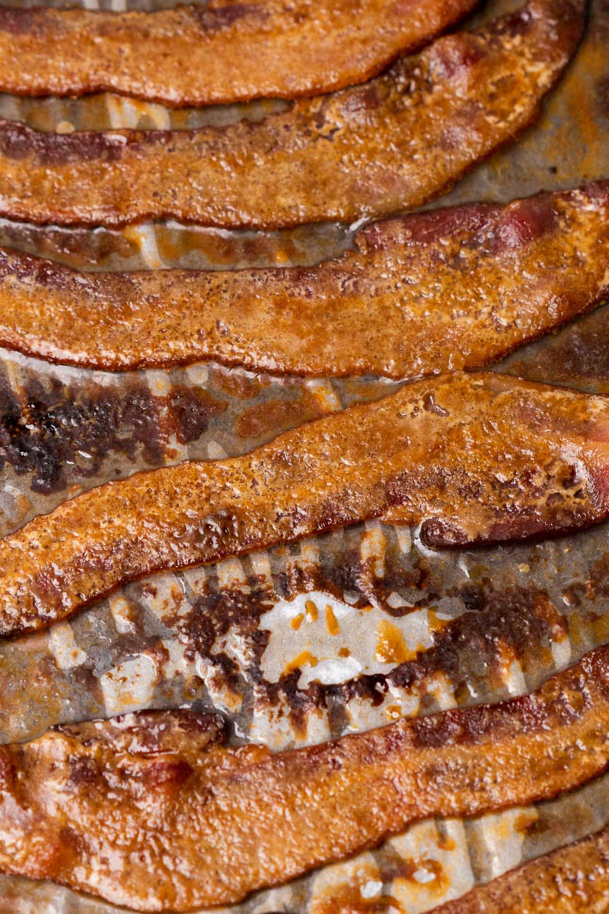 cooked candied bacon on a sheet of white parchment paper