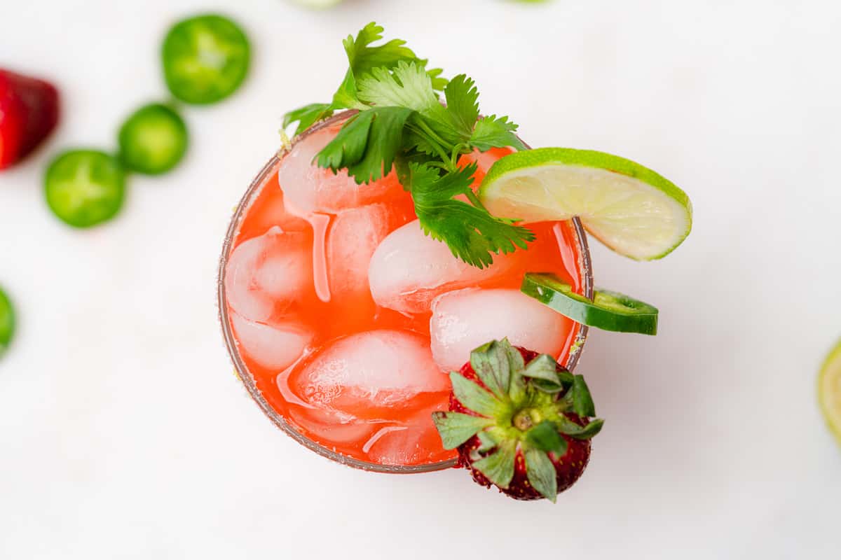 overhead view of strawberry jalapeño margarita with lime and cilantro
