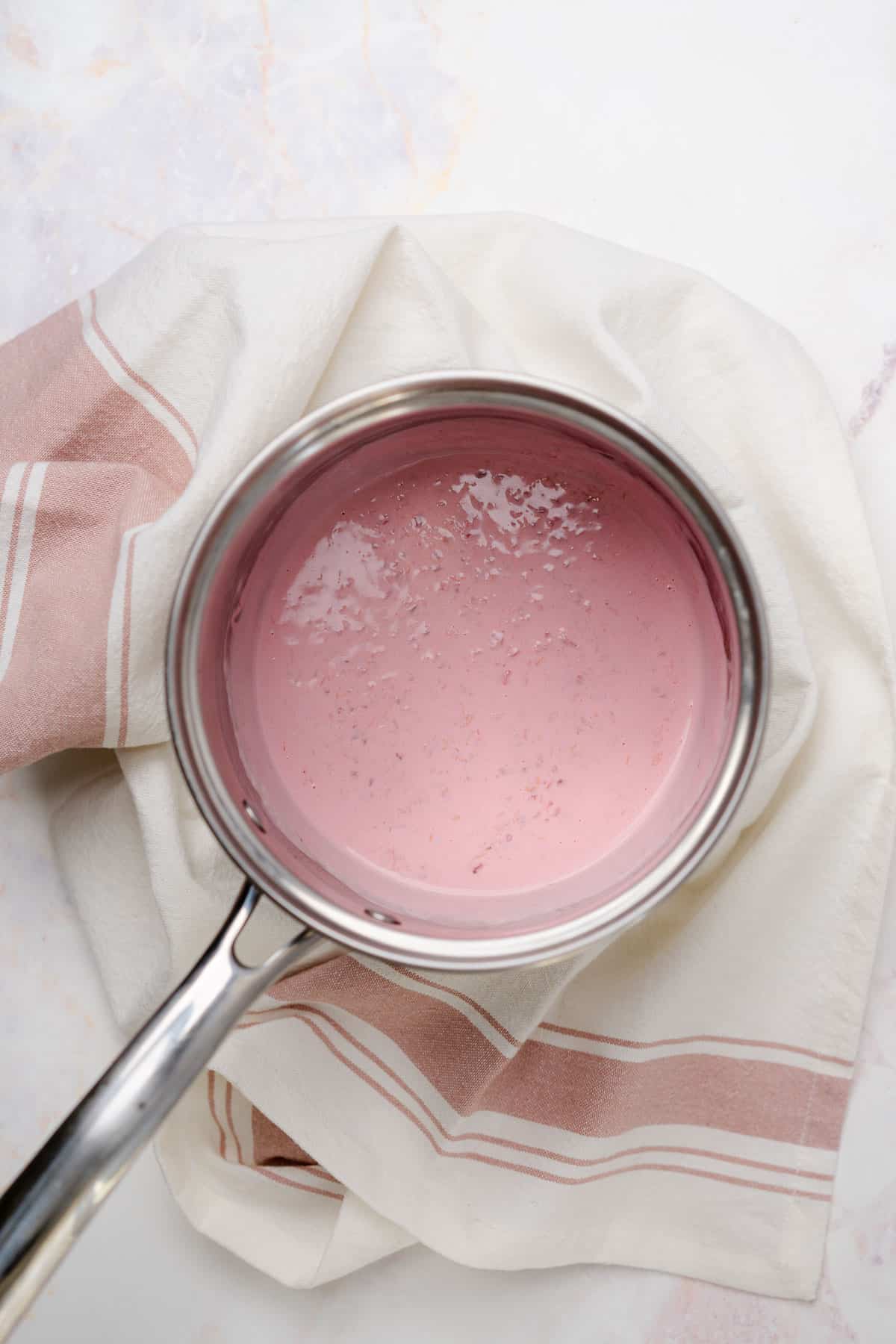 cooked cream and raspberries in a sauce pan 
