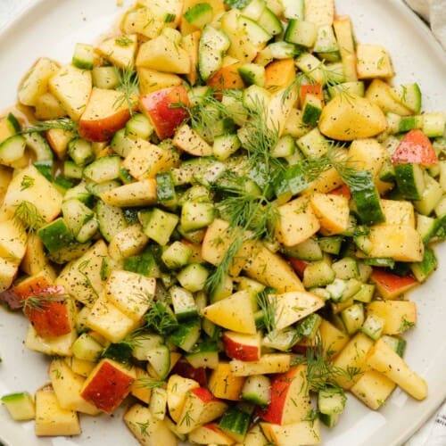 close up shot of apple and cucumber salad with dill and fresh dressing