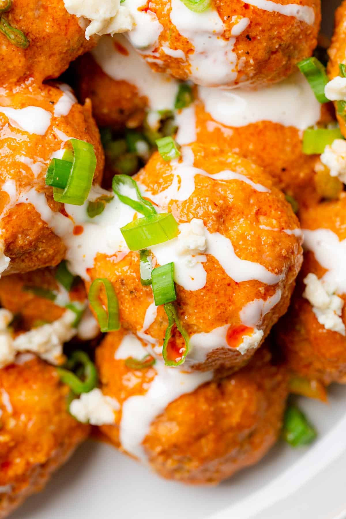 close up shot of turkey meatballs with buffalo sauce and green onions blue cheese dressing