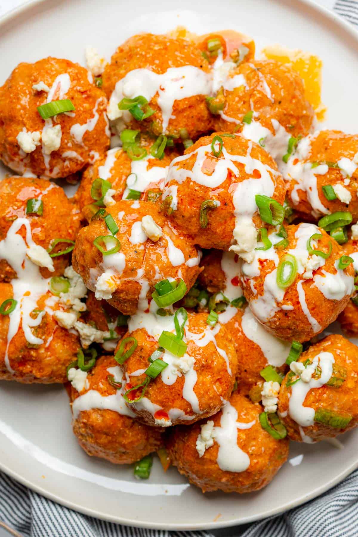 up close shot of buffalo turkey meatballs drizzled with blue cheese dressing and green onions