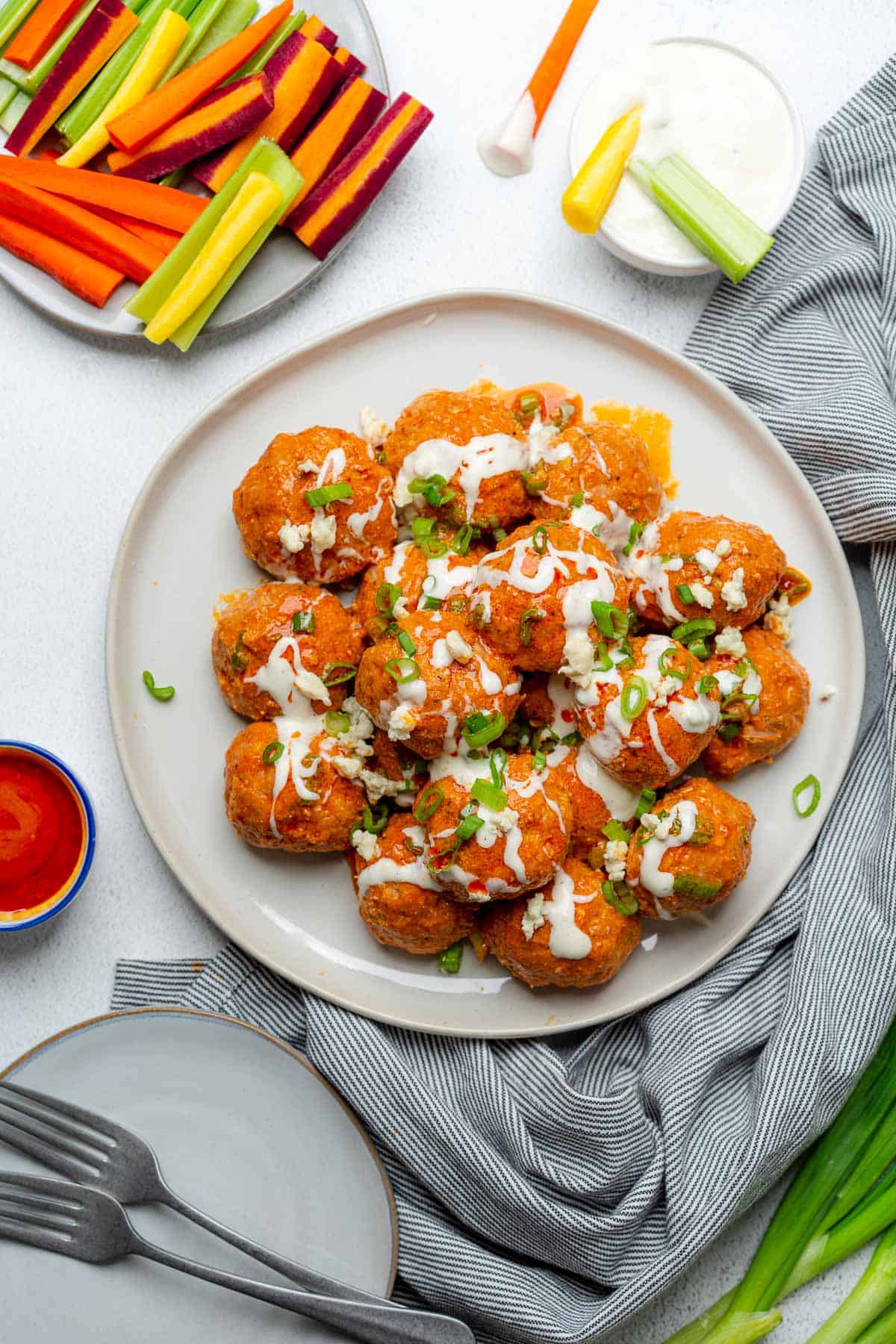 buffalo turkey meatballs on a plate with blue cheese dressing green onions carrots and celery