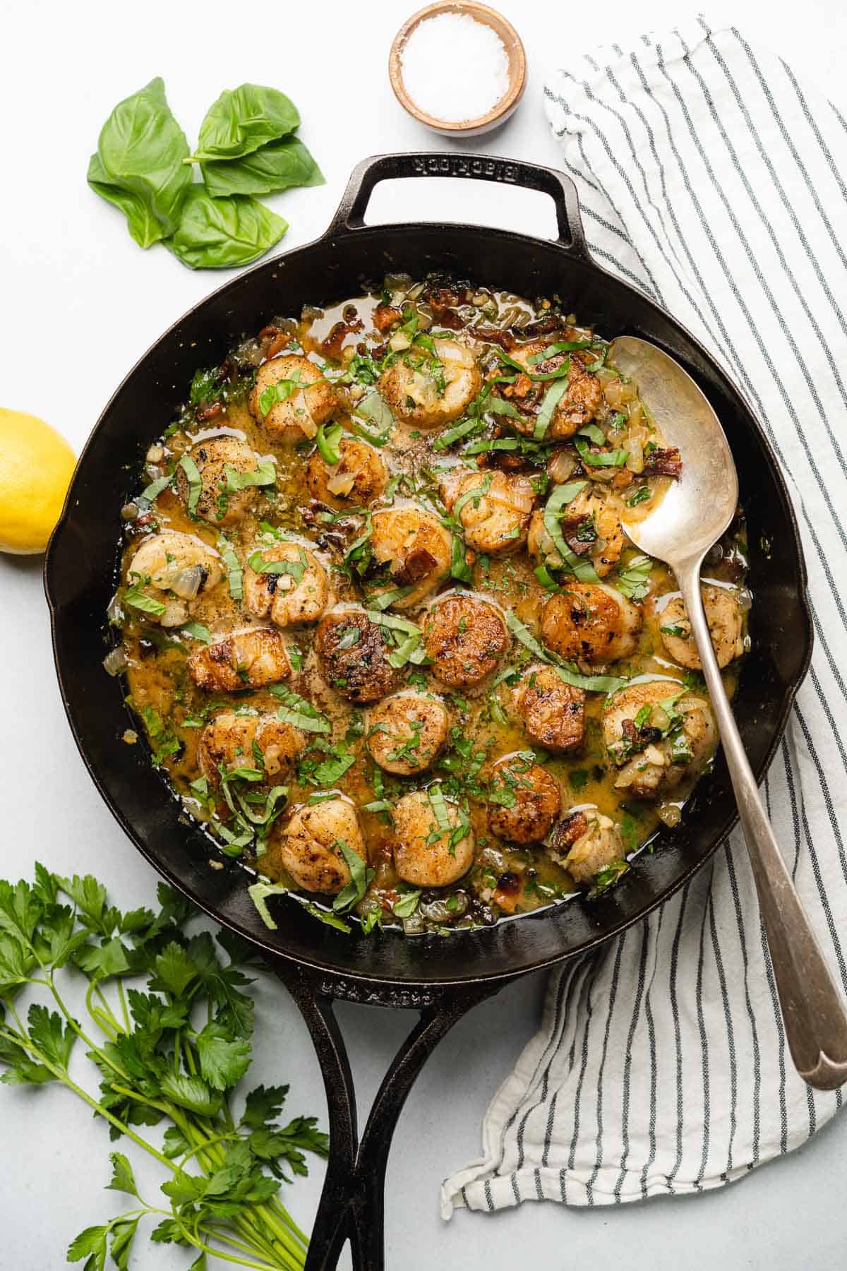 scallops in a cast iron skillet with a creamy butter lemon pan sauce with bacon and basil