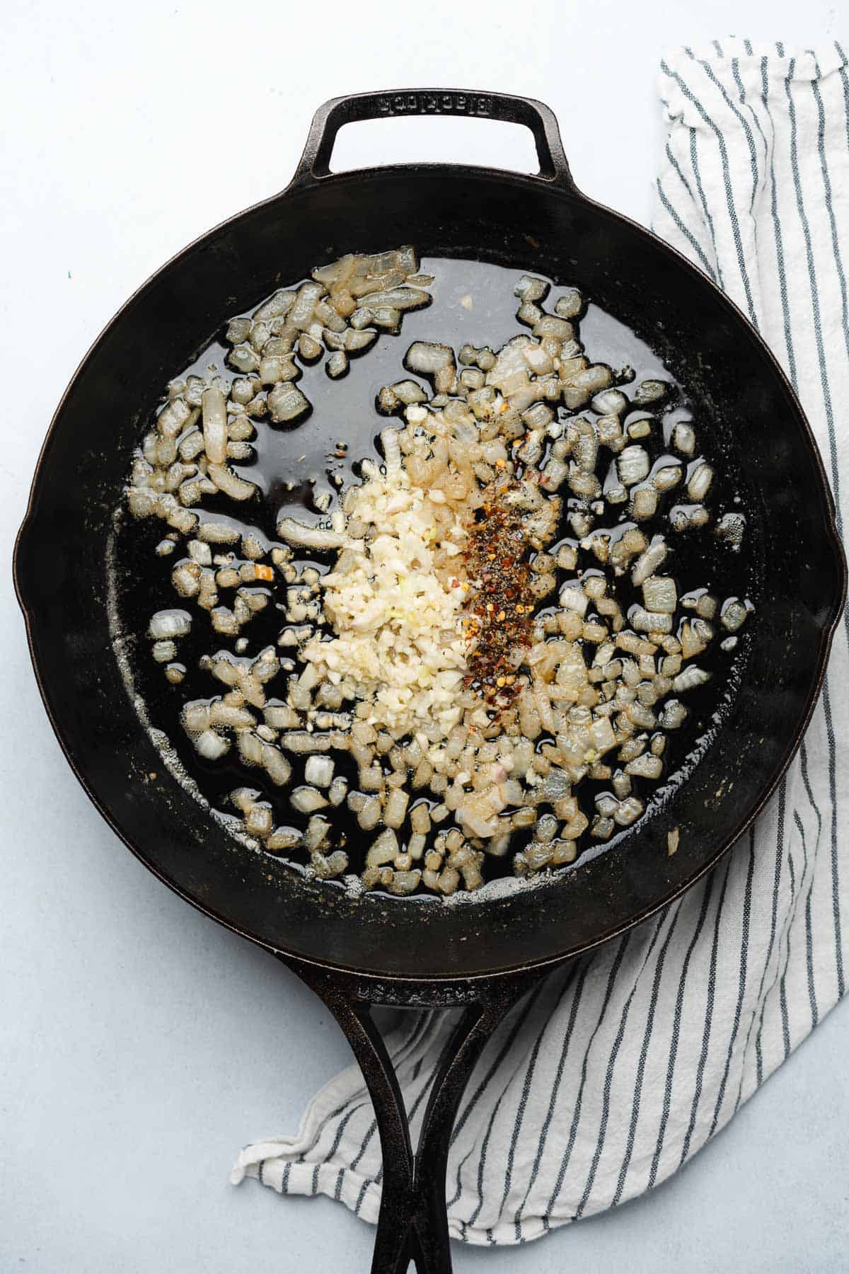 seasonings with garlic and onions in a cast iron skillet