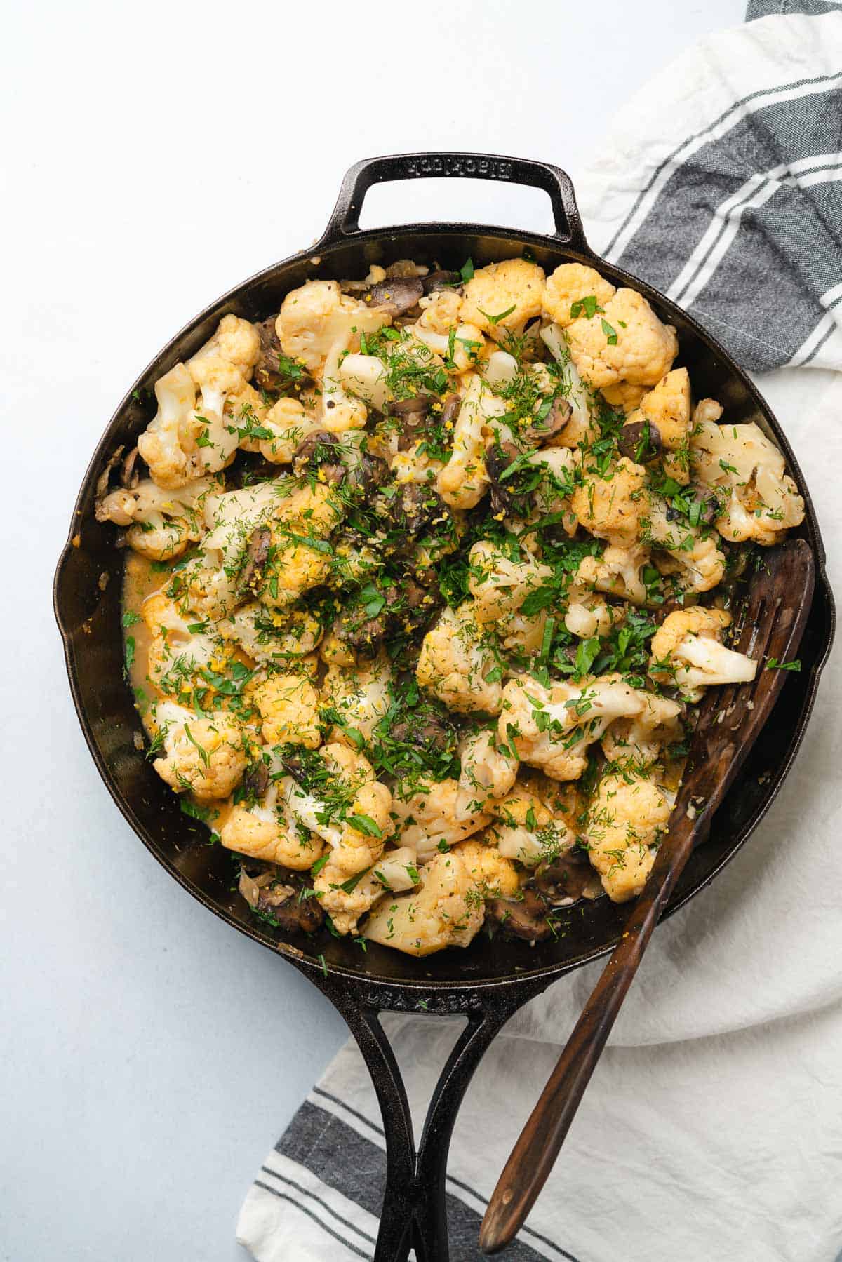 cauliflower and mushrooms with fresh parsley and dill in a cast iron skillet