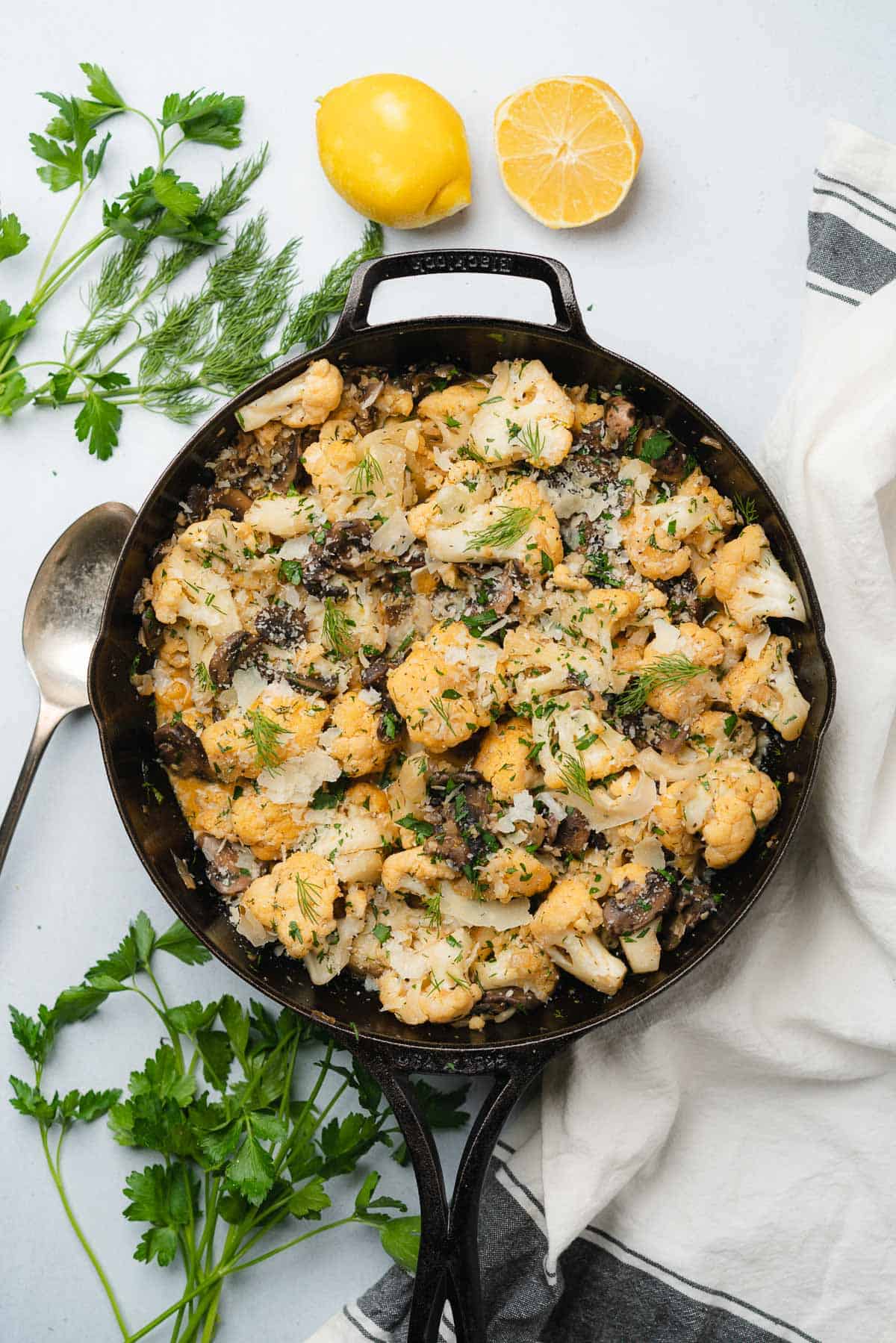 cast iron skillet with cauliflower and mushrooms with garlic lemon butter sauce and parmesan