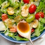 spoonful of creamy balsamic dressing on an arugula side salad with cherry tomatoes