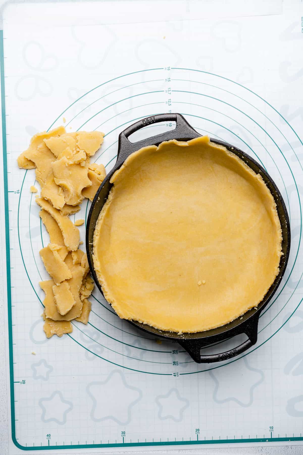 raw gluten free pie crust dough inside of a cast iron skillet with extra dough around the sides