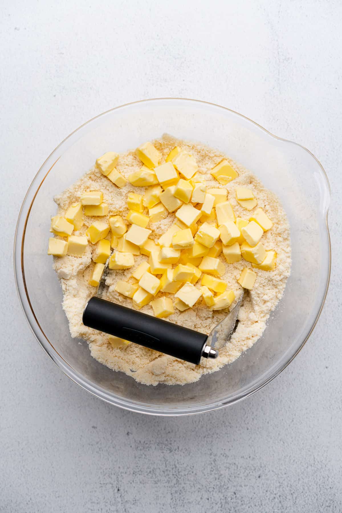 cold butter chunks in a bowl with a pastry cutter 