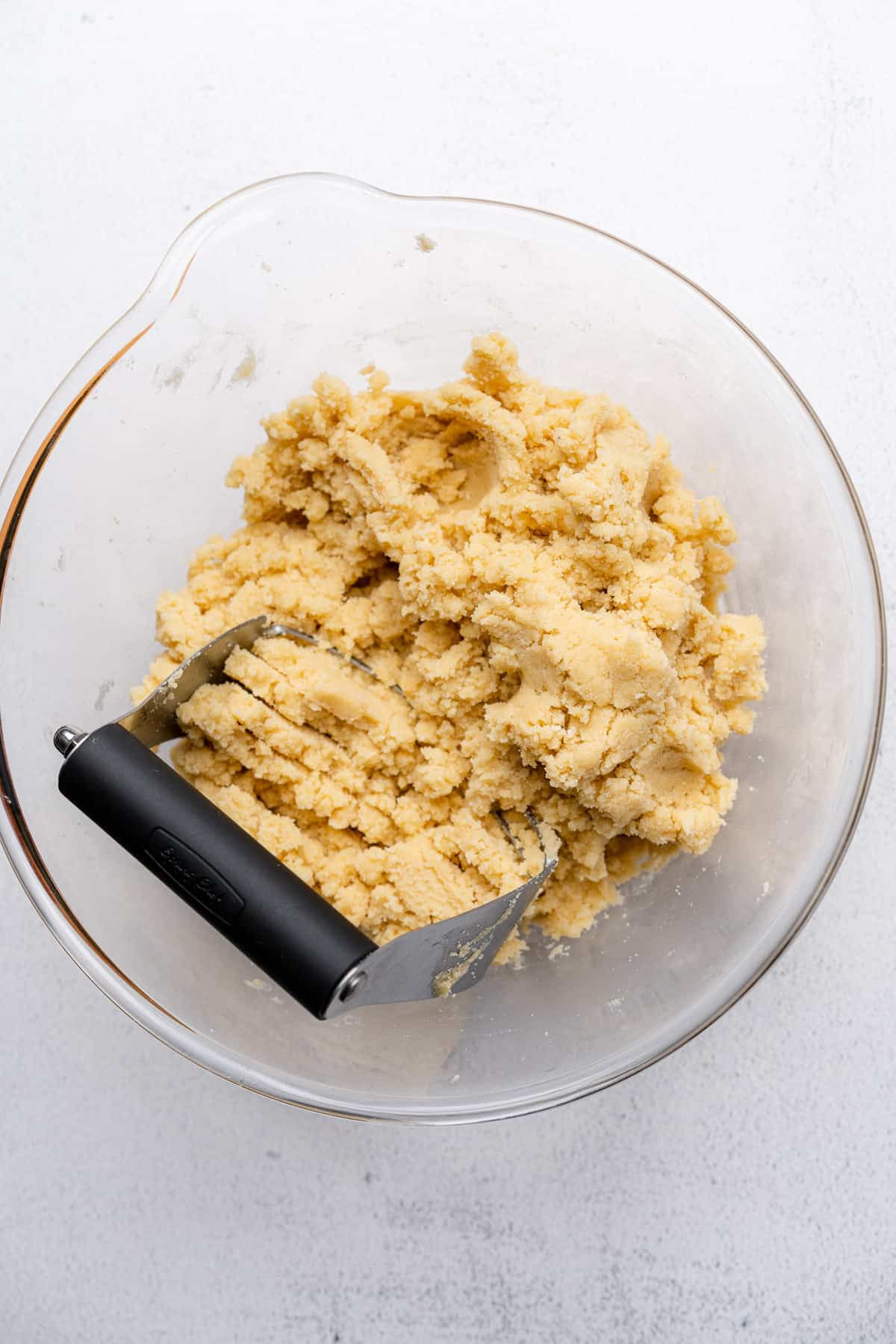 dough coming into shape in a glass bowl with a pastry cutter