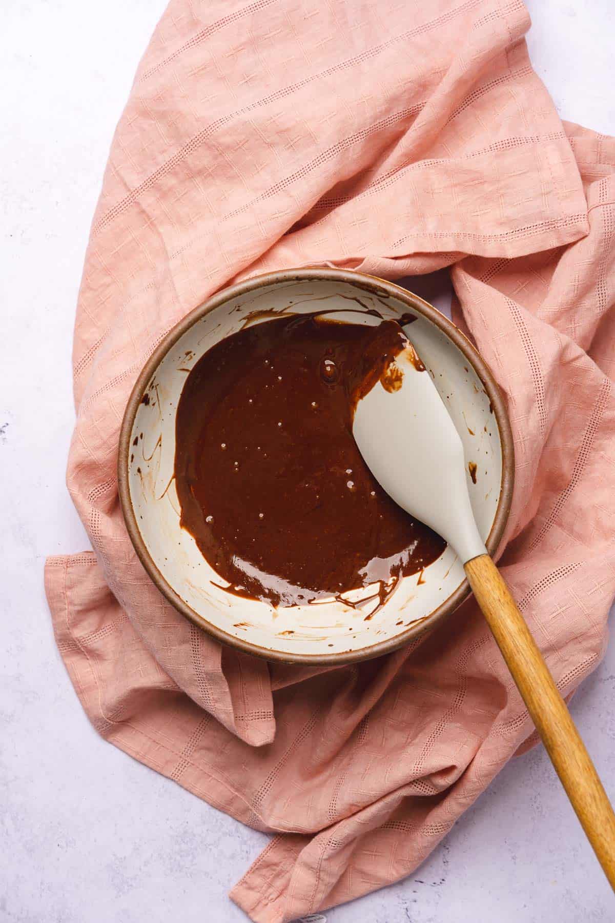 mixing chocolate ganache in a ceramic bowl with a rubber spatula