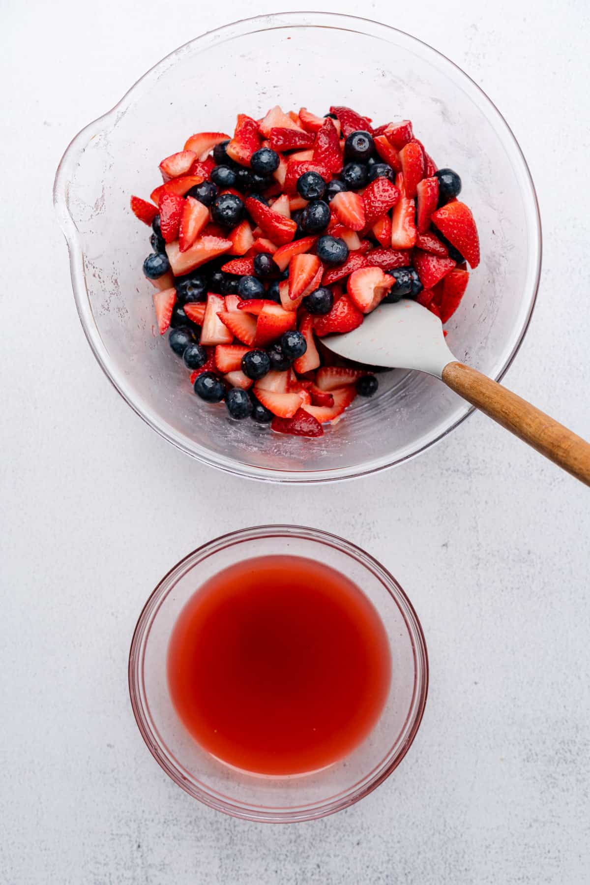 strained berry juice in a bowl next to a large bowl of berries