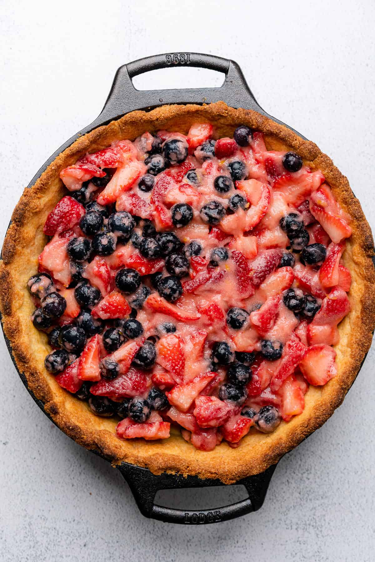 prepared berries inside of a browned pie crust in a cast iron skillet