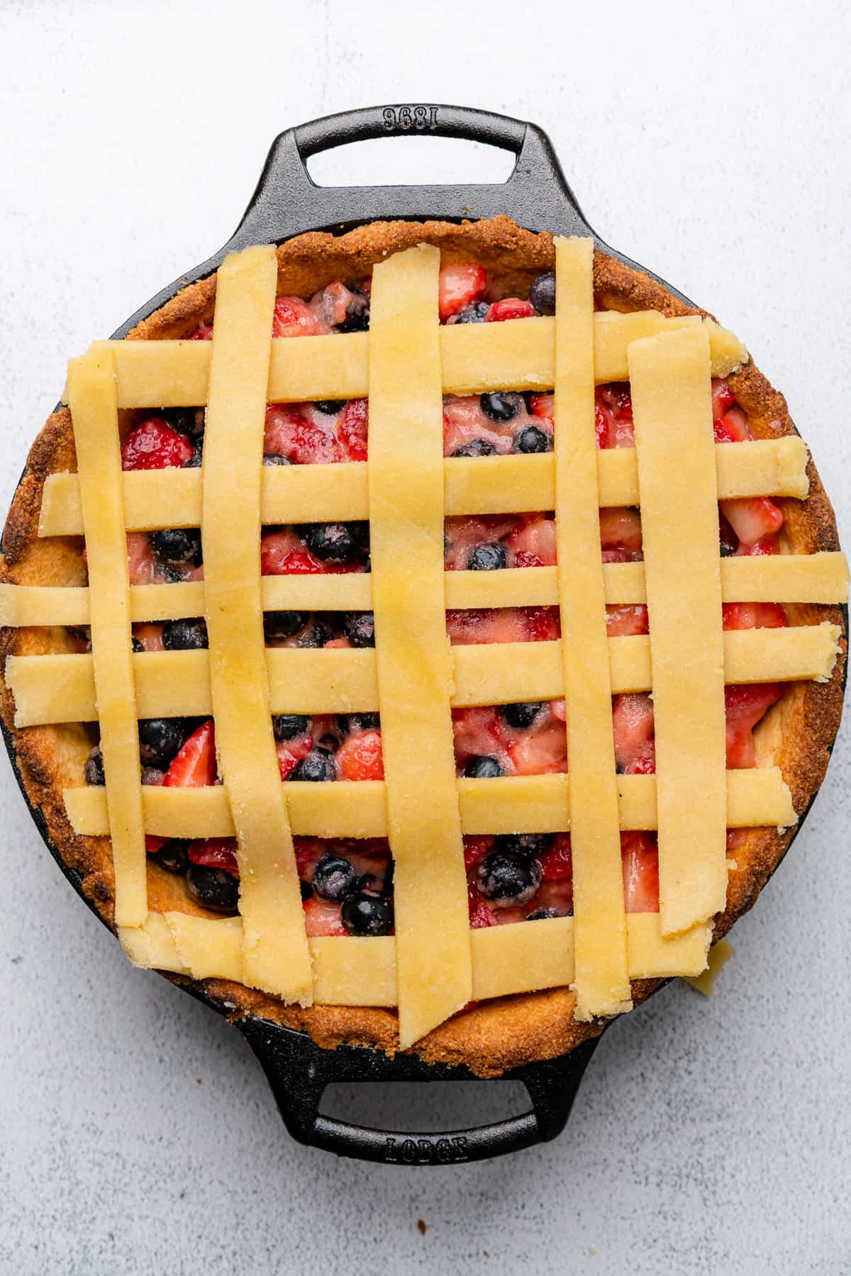 raw gluten free pie crust lattice like shape on top of a strawberry blueberry pie